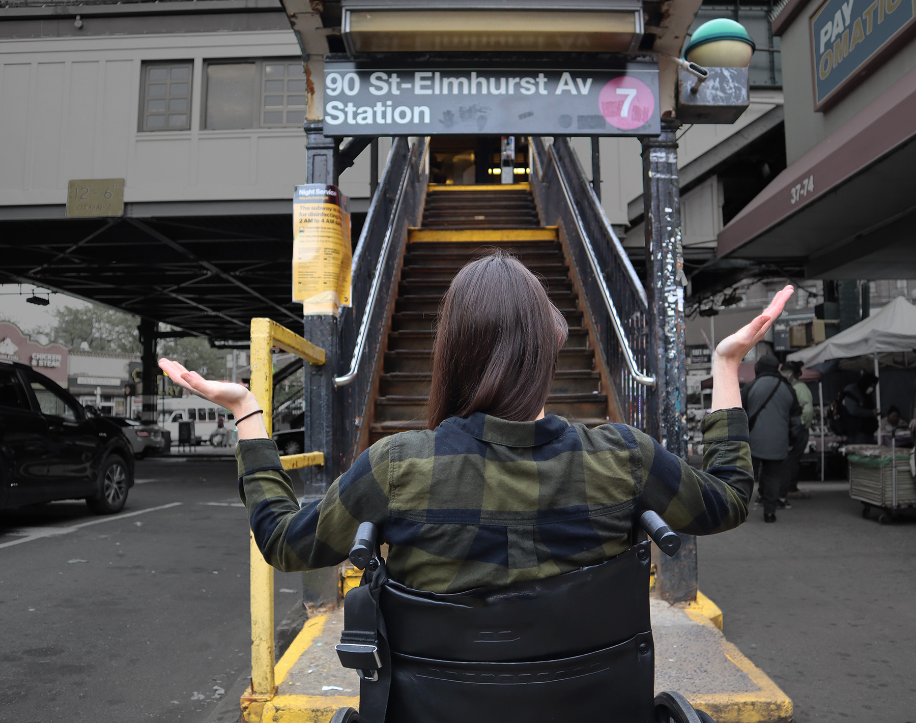 Person in wheelchair in front of subway station staircase wondering how to go up